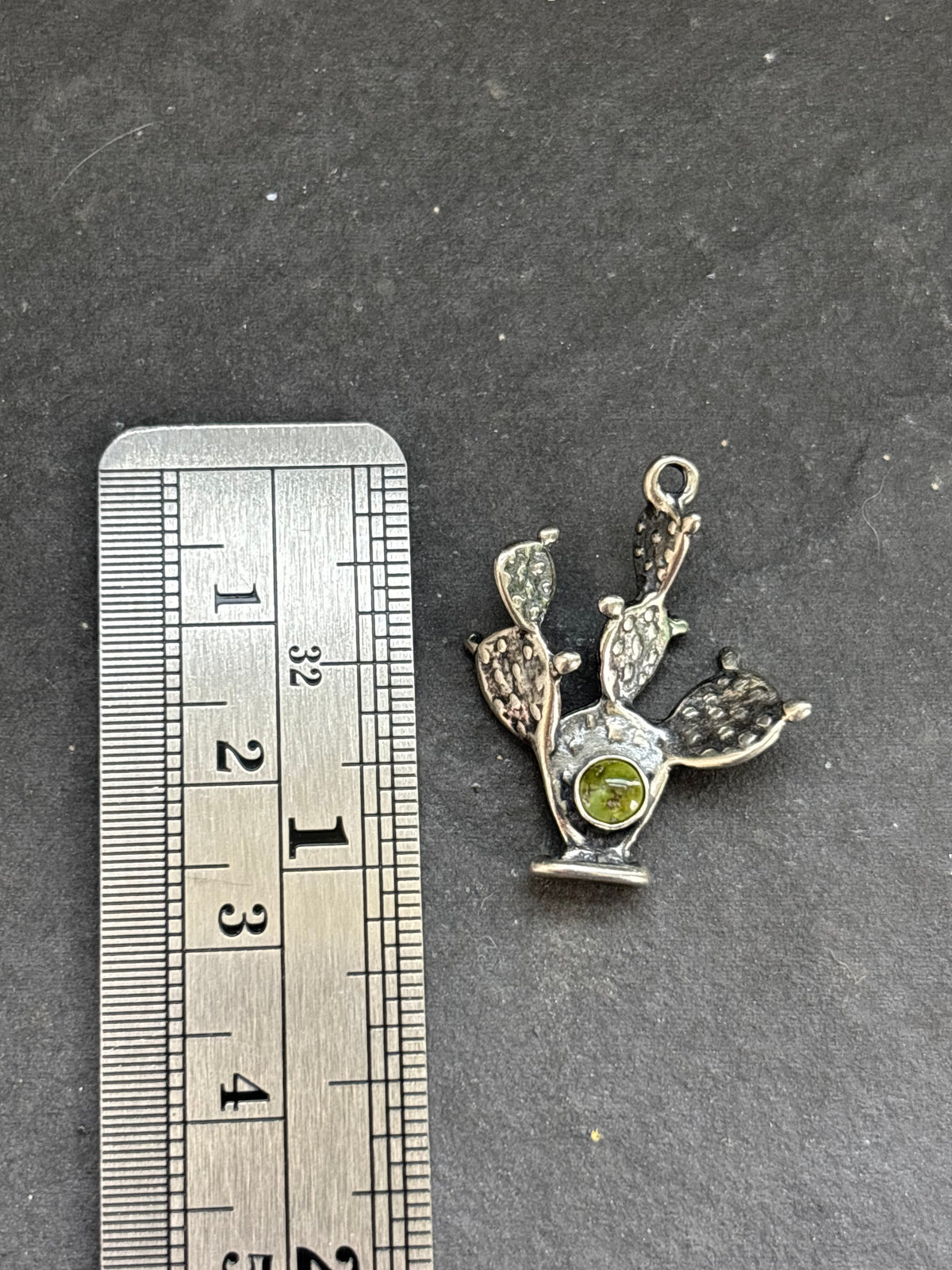 Sonoran Gold Prickly Pear Cactus Charm in sterling silver, beside a vertical ruler for scale