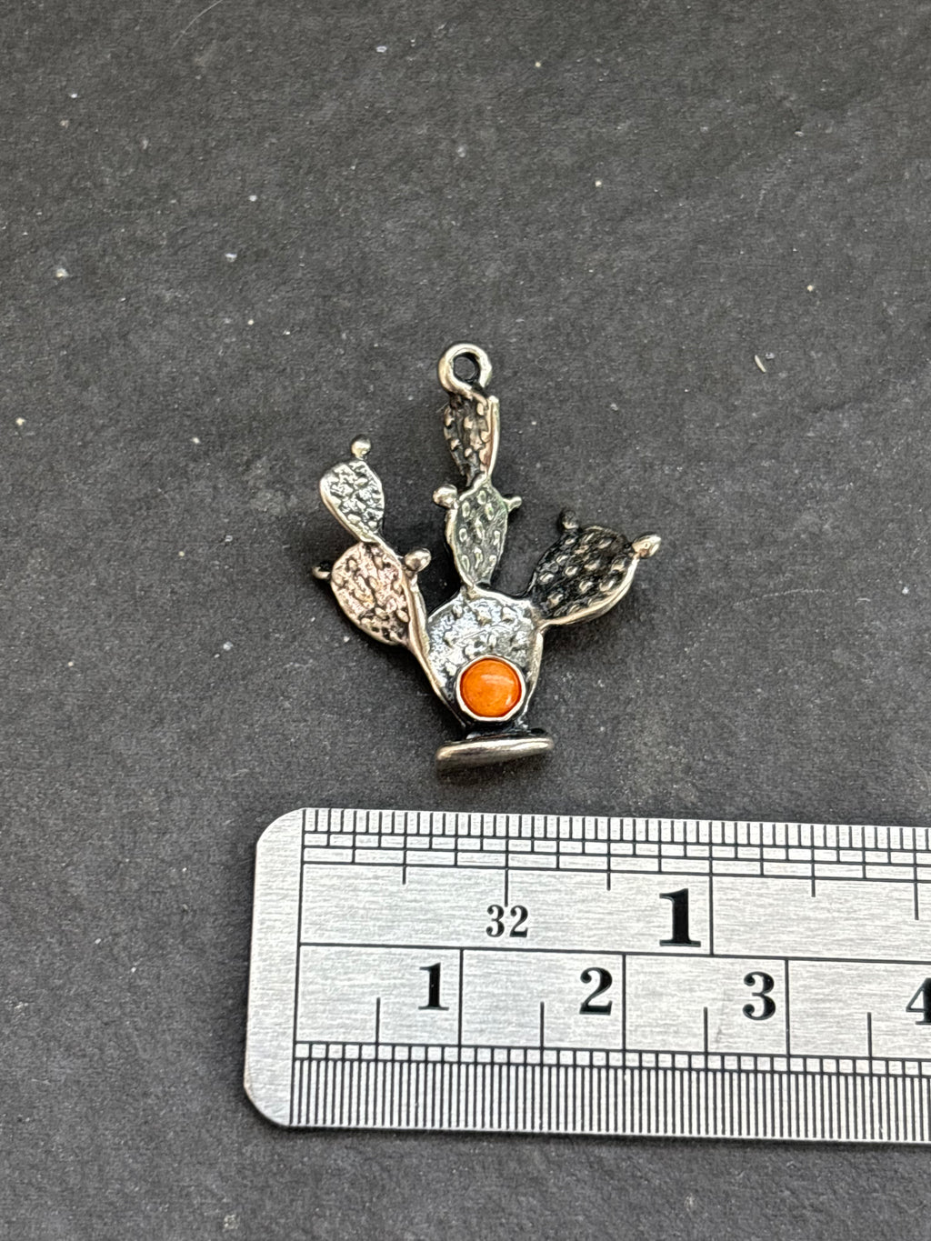 Orange Spiny Oyster Prickly Pear Cactus Charm in sterling silver, beside a horizontal ruler for scale