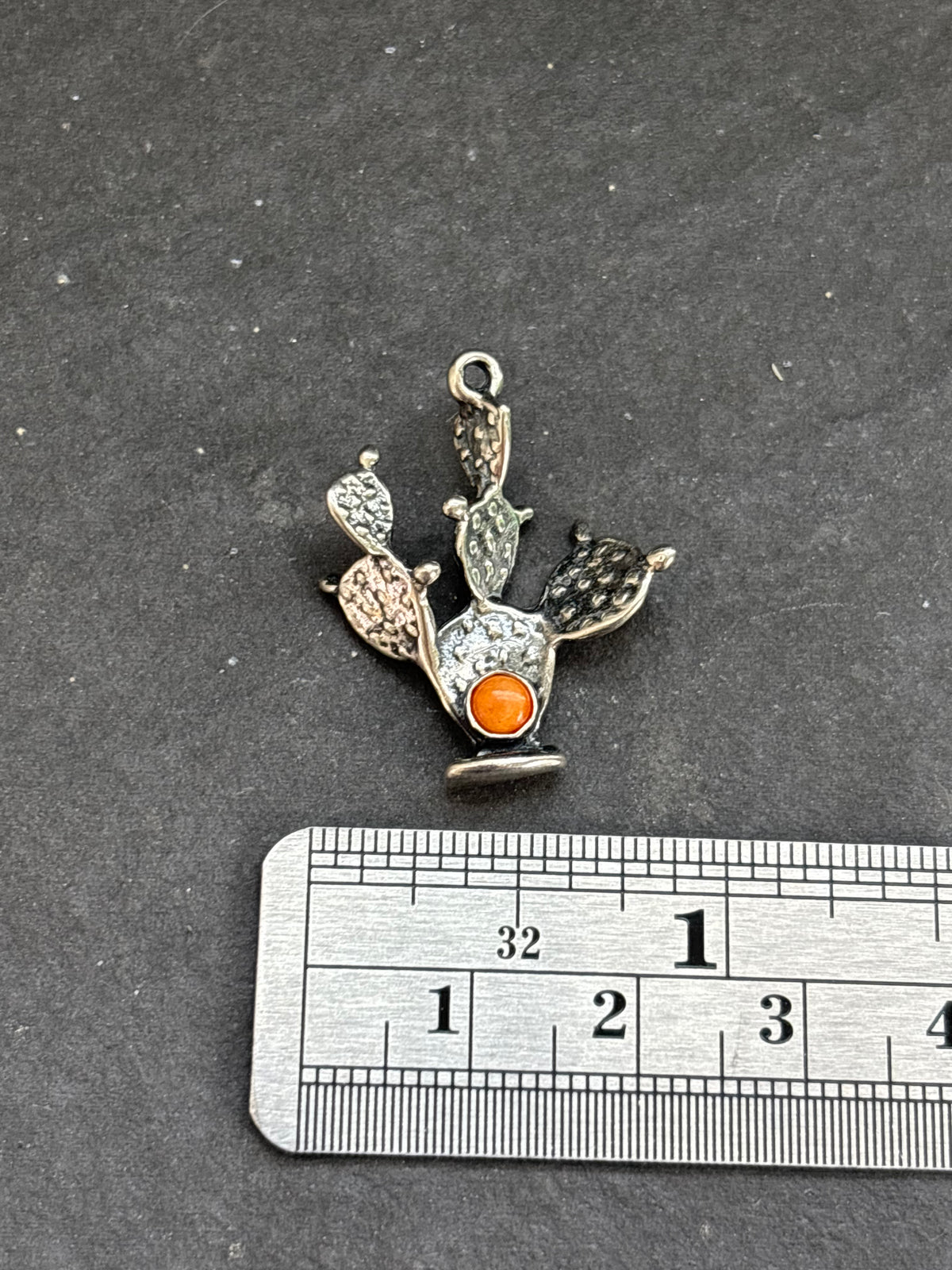 Orange Spiny Oyster Prickly Pear Cactus Charm in sterling silver, beside a horizontal ruler for scale