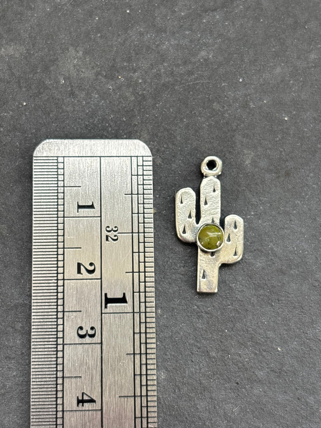 Sonoran Gold Saguaro Cactus Charm in sterling silver, beside a vertical ruler for scale
