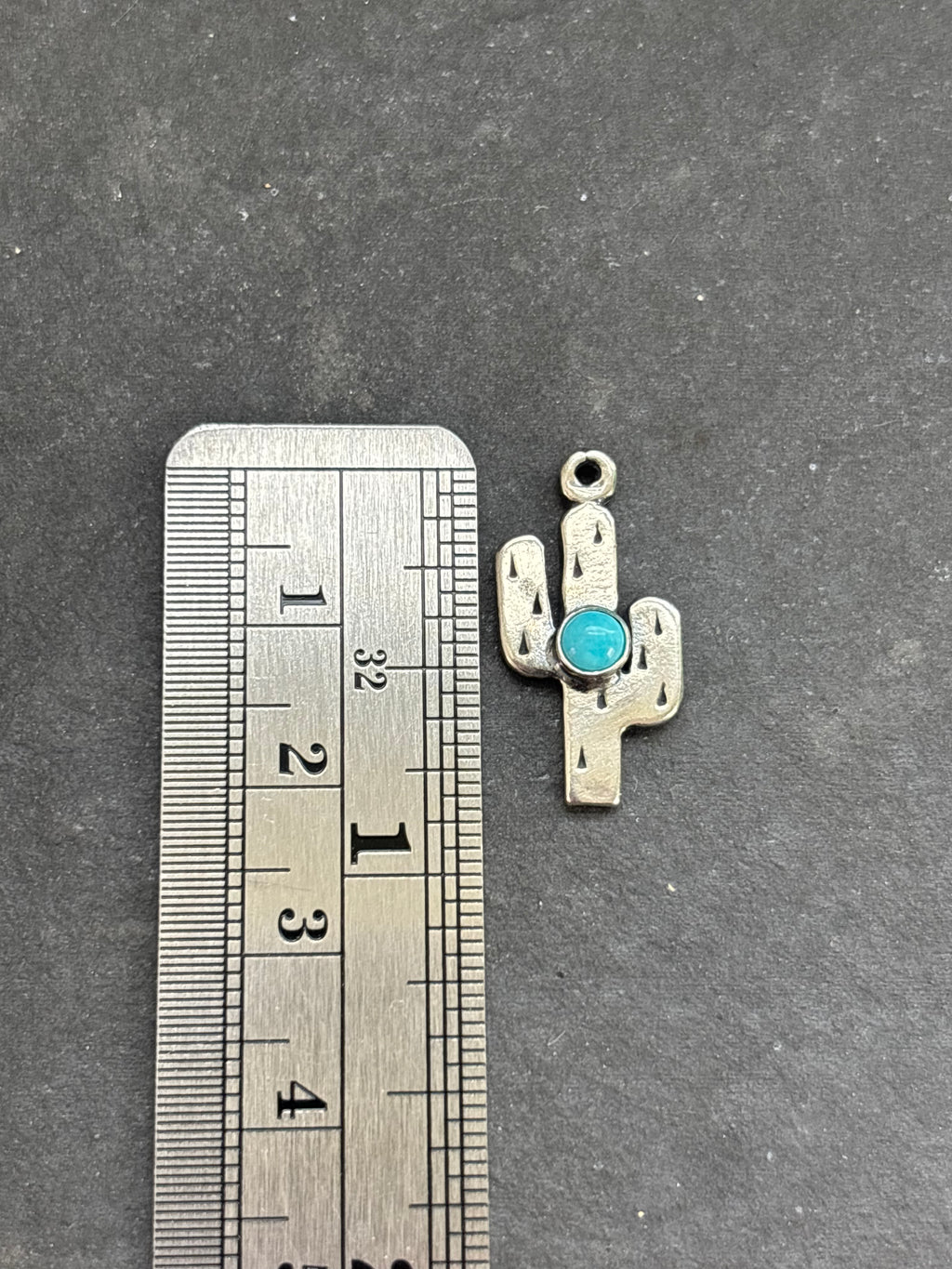 Light Blue Kingman Turquoise Saguaro Cactus Charm in sterling silver, beside a vertical ruler for scale