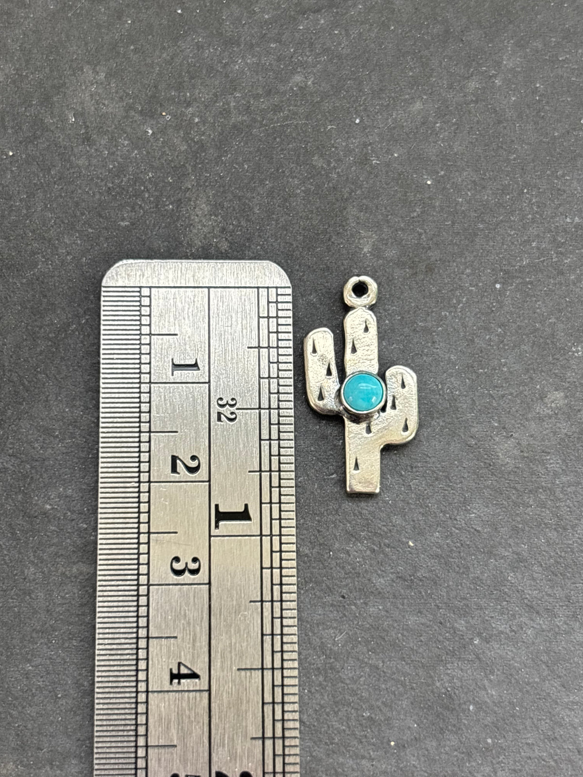 Light Blue Kingman Turquoise Saguaro Cactus Charm in sterling silver, beside a vertical ruler for scale