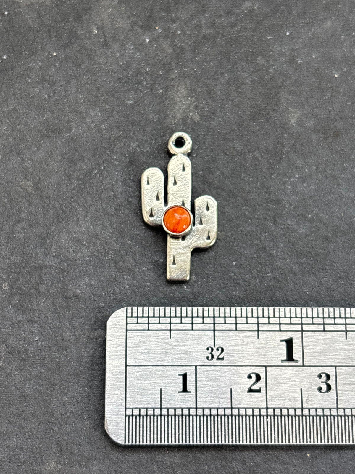 Orange Spiny Oyster Saguaro Cactus Charm in sterling silver, beside a horizontal ruler for scale