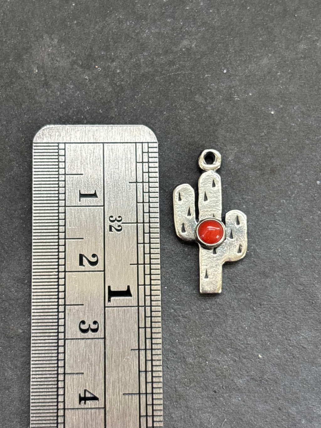 Red Spiny Oyster Saguaro Cactus Charm in sterling silver, beside a vertical ruler for scale